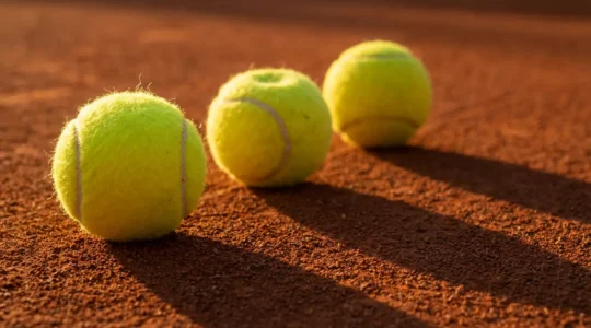 Comparaison visuelle entre différents types de balles de tennis sur un court extérieur français