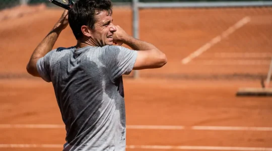Joueur de tennis en t-shirt mouillé de sueur sur court de terre battue française sous le soleil