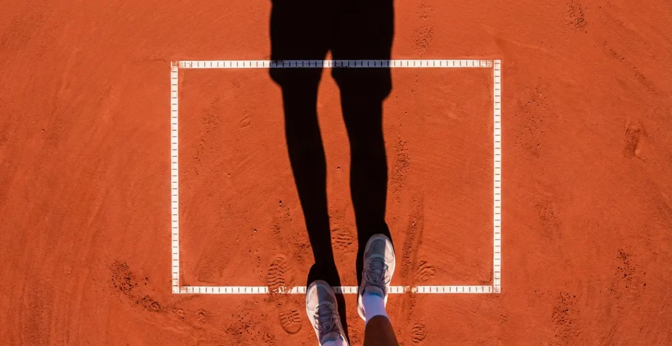 Vue aérienne minimaliste d'un joueur en position de service montrant l'alignement parfait des appuis