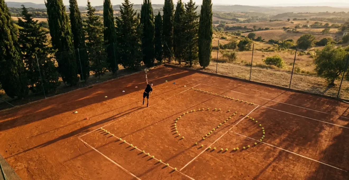Joueur de tennis concentré sur un court en terre battue durant un entraînement technique intensif